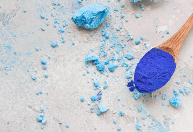 blue majik spirulina powder in a wooden spoon