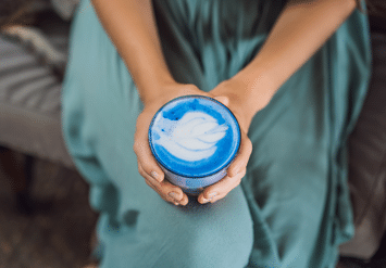 woman holding a cup of blue smoothie