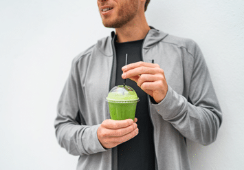 man holding a green smoothie
